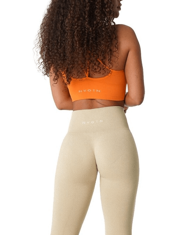 Back view of woman wearing beige tight elastic leggings and orange sports top for fitness activities